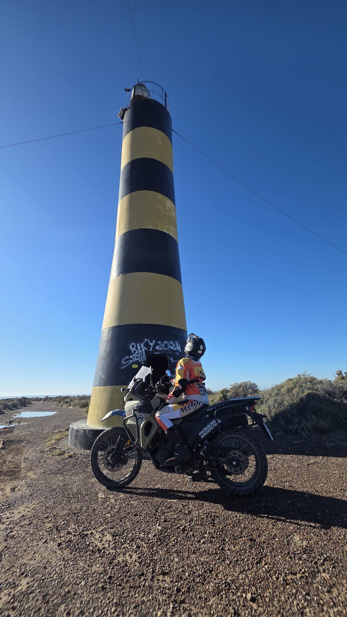 Moto y conductor de moto frente al faro de Punta Ninfa